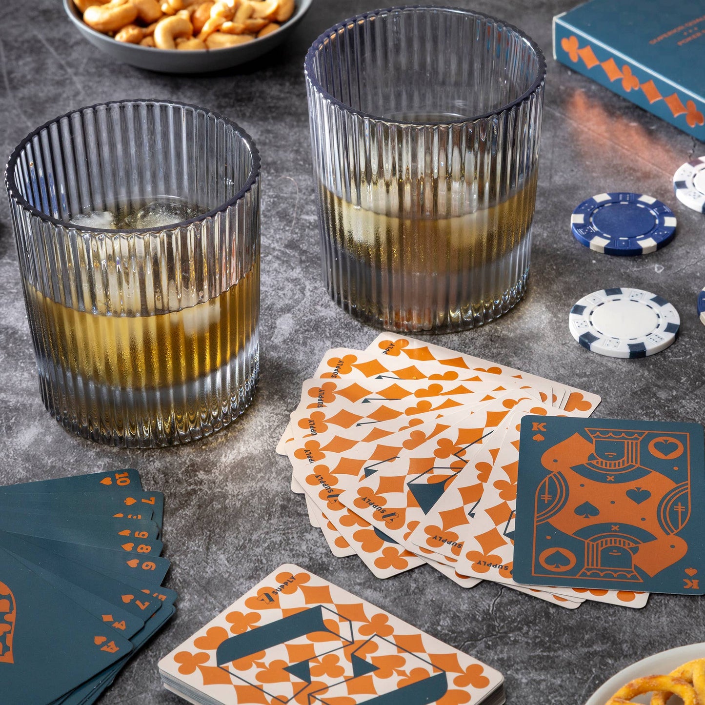 Two glasses with a drink, playing cards, and poker chips on a table.