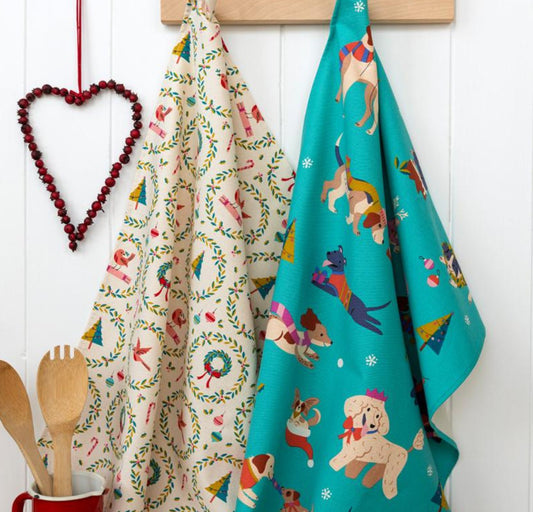 Two patterned towels hanging on a wooden rack with a heart-shaped decoration and wooden utensils.
