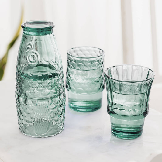 Set of green glass bottles and tumblers on a light background