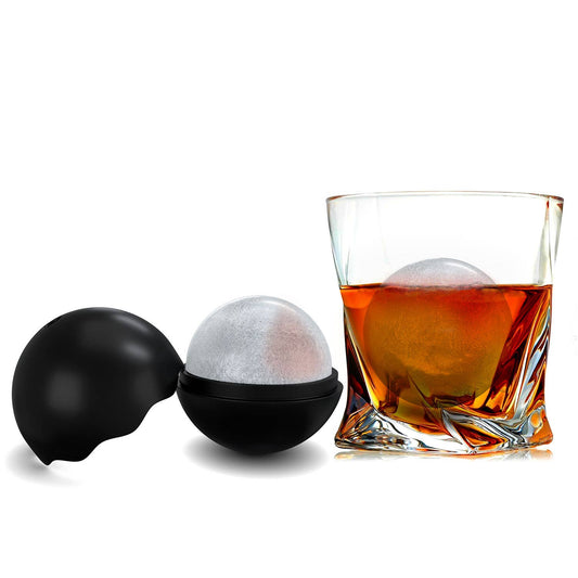 Black ice mold with a sphere of ice and a glass of whiskey on a white background