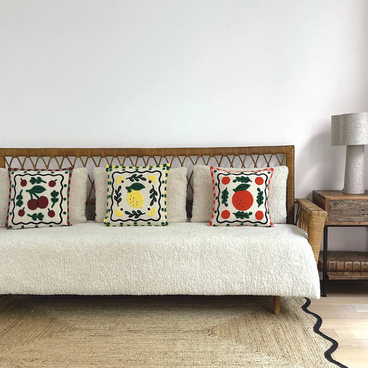 Decorative pillows on a sofa with a wooden headboard and lamp in a room setting.