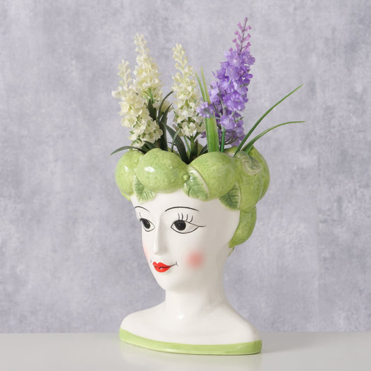 Vase shaped like a woman's head with floral arrangement on a gray background