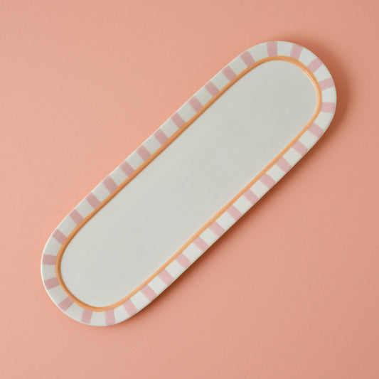Rectangular tray with pink and white striped border on a pink background