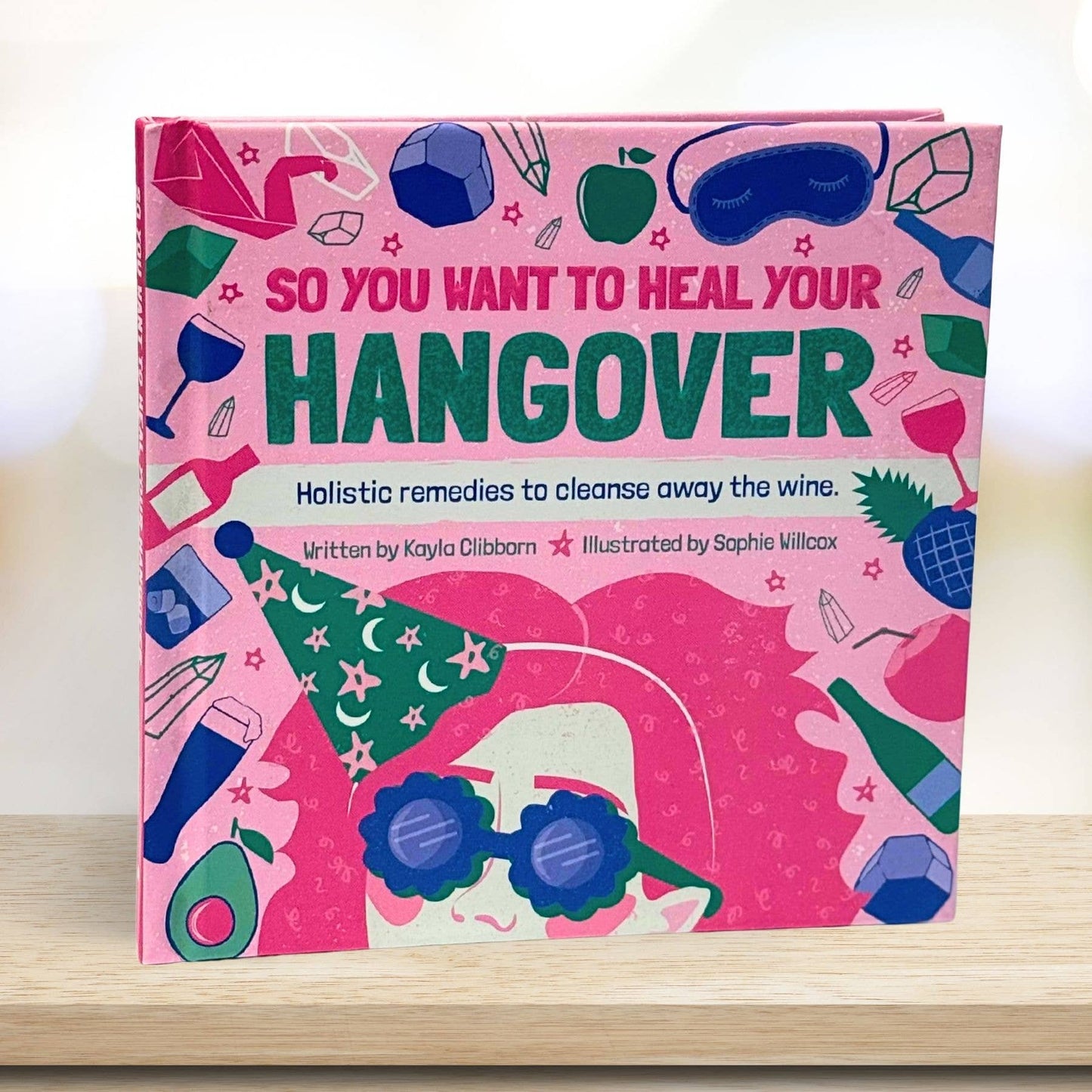 Book titled 'So You Want to Heal Your Hangover' with colorful illustrations on a pink background