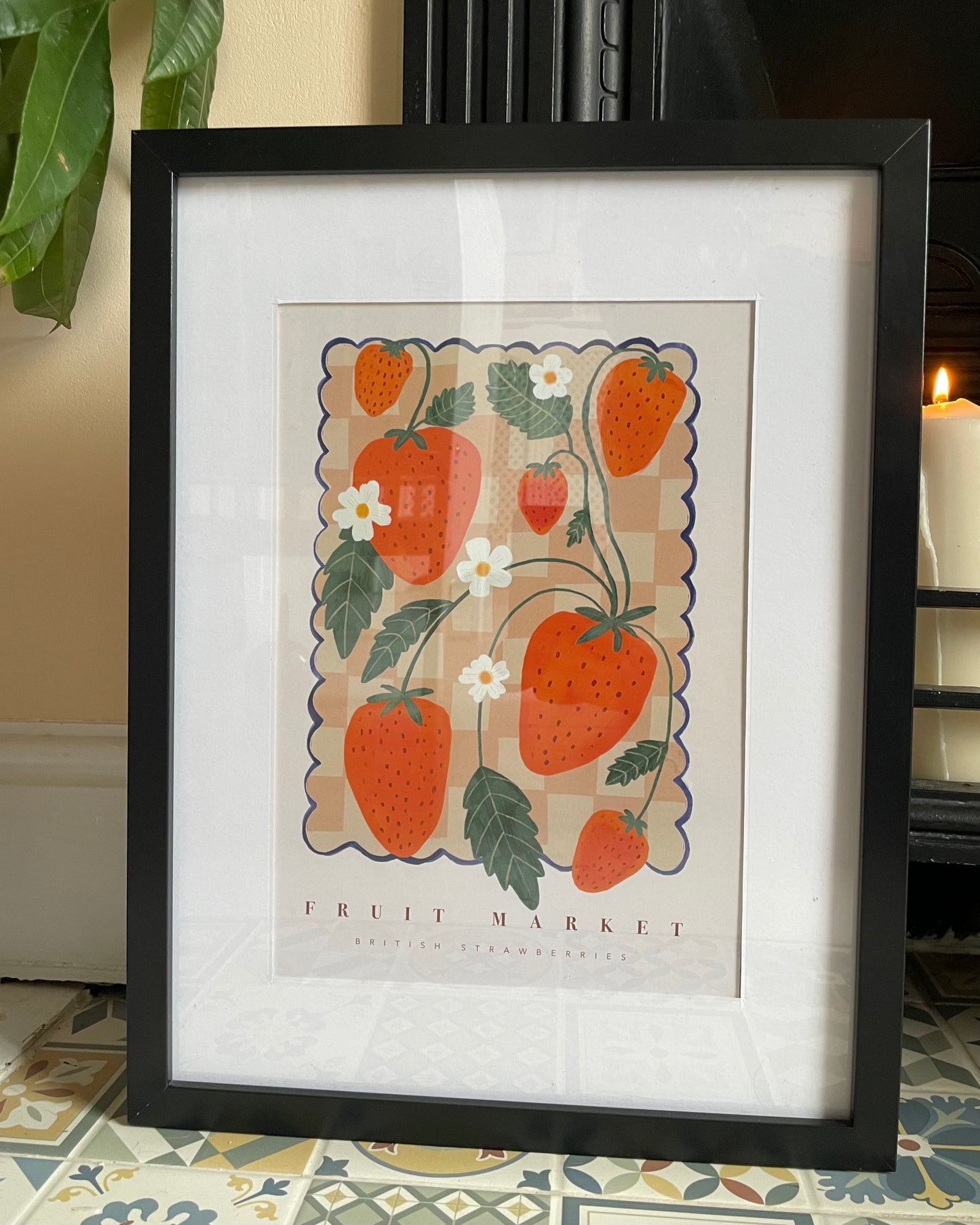 framed strawberry fruit market print next to fireplace with candle