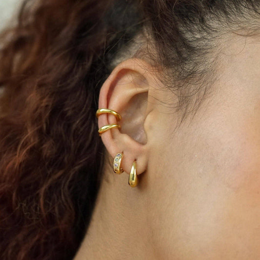Close-up of an ear with gold earrings and hair in the background