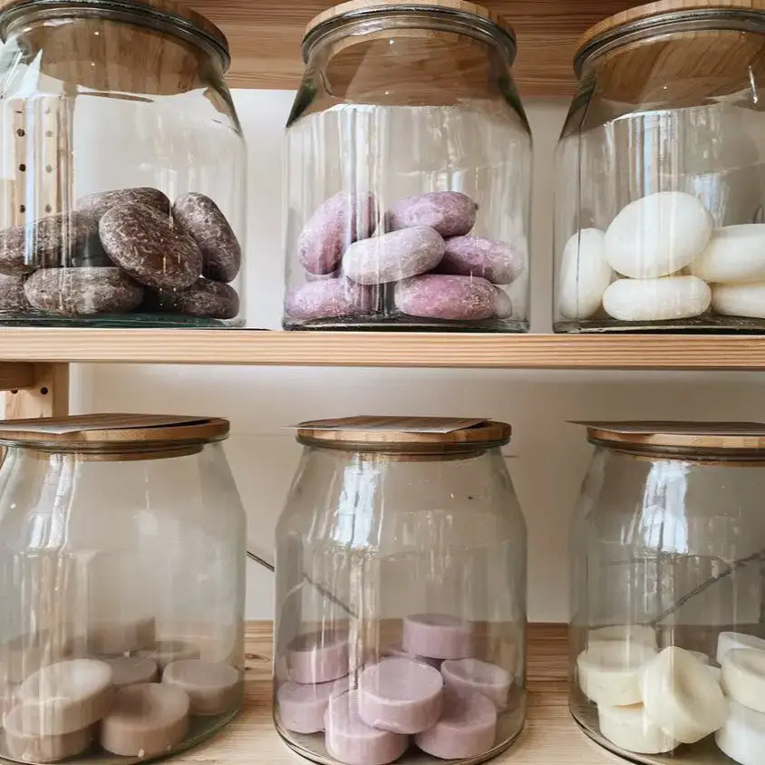 Glass jars with wooden lids containing various round items on a shelf.