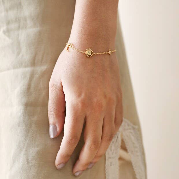 Gold bracelet on a person's wrist with a neutral background