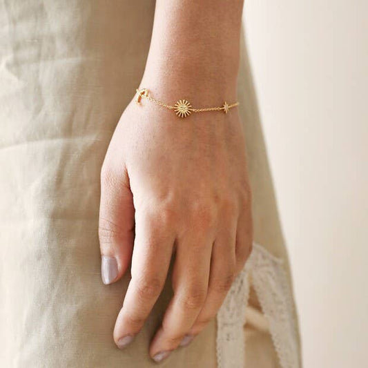 Gold bracelet on a person's wrist with a neutral background