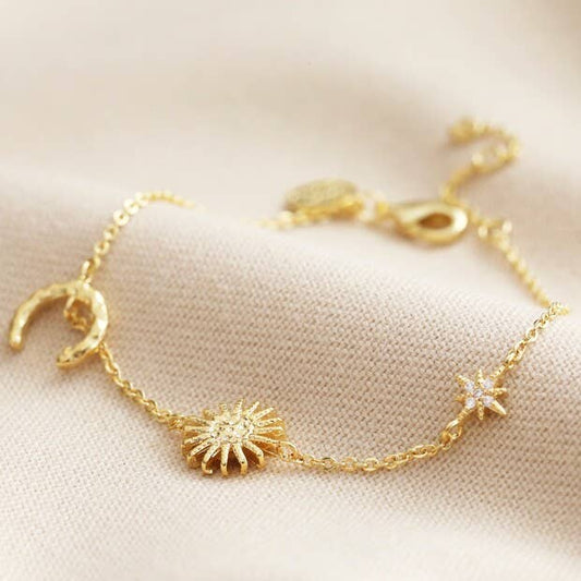 Gold bracelet with sun, moon, and star charms on a soft beige background