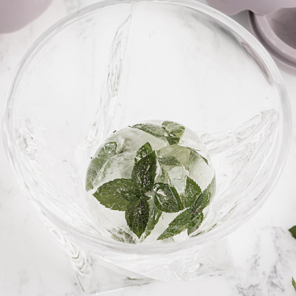 Clear glass with ice cubes and mint leaves on a marble surface