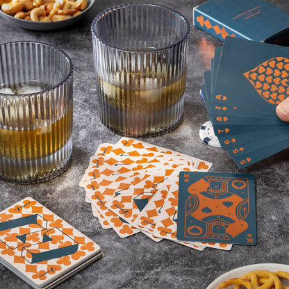 Playing cards with unique design on a table with glasses and snacks