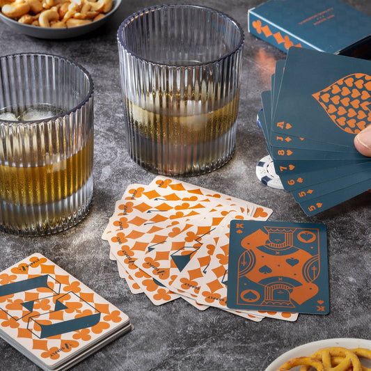 Playing cards with unique design on a table with glasses and snacks