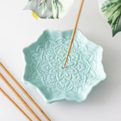 Turquoise ceramic incense holder with decorative patterns on a white background