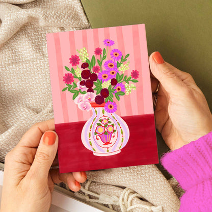 Hand holding a small card with floral design and striped pattern
