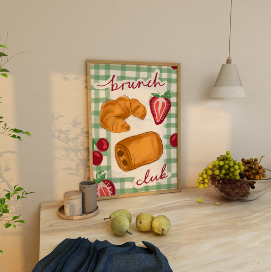 Framed artwork with 'Brunch Club' design on a table with fruits and decor.