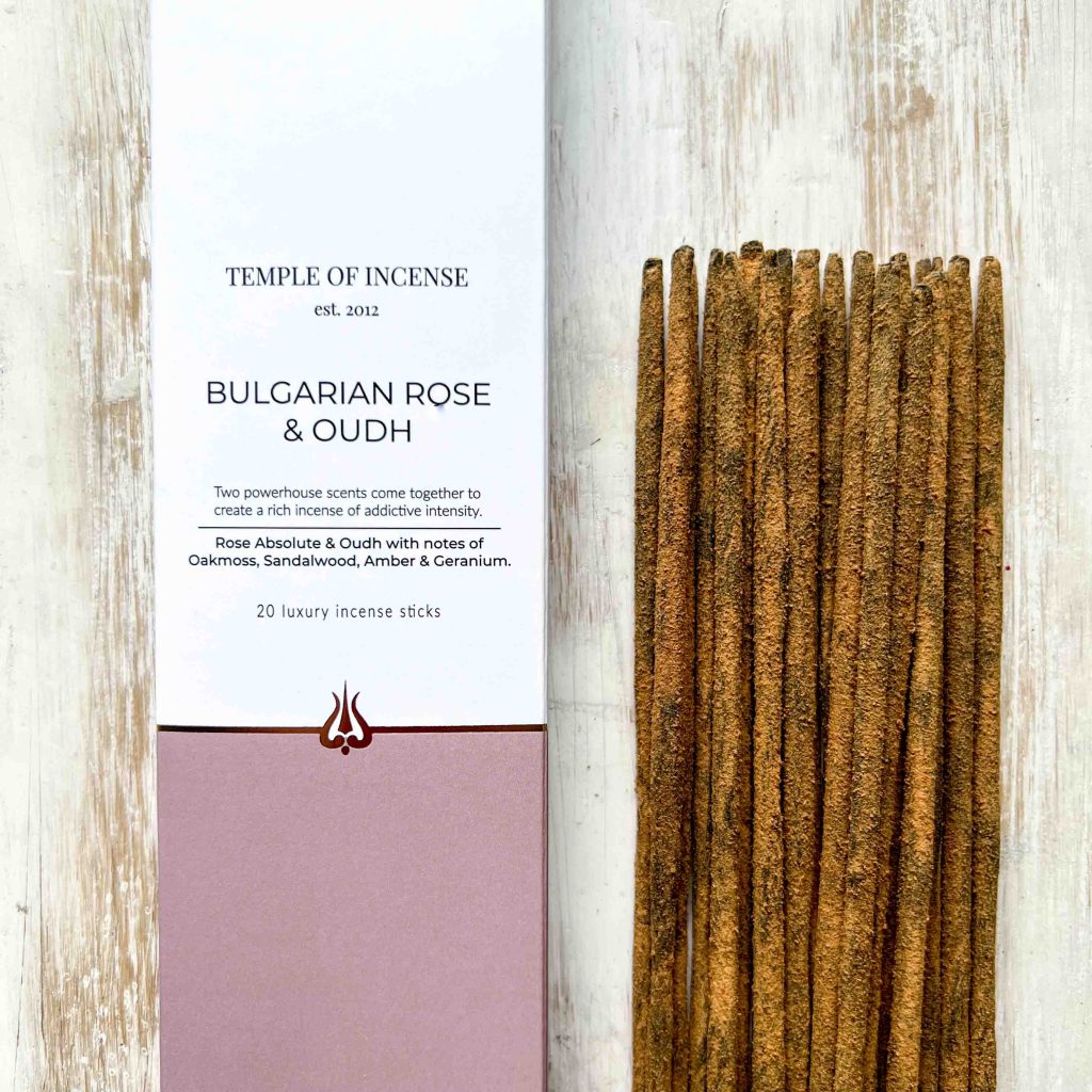 A package of 'Bulgarian Rose & Oudh' incense sticks by Temple of Incense, with the incense sticks spilling out in front of the package which is labeled with product information.