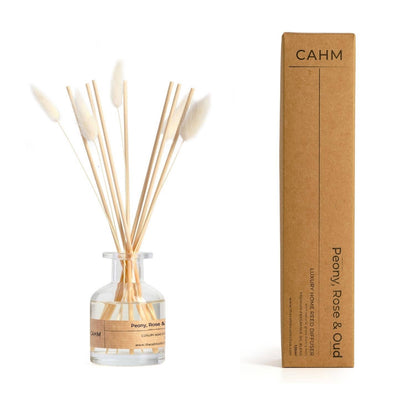 Reed diffuser set with bottle and sticks next to its cardboard box on a white background