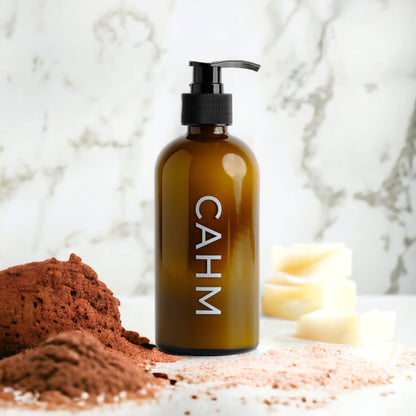 Brown bottle with pump labeled 'CAHM' on a marble surface with brown powder and white blocks.
