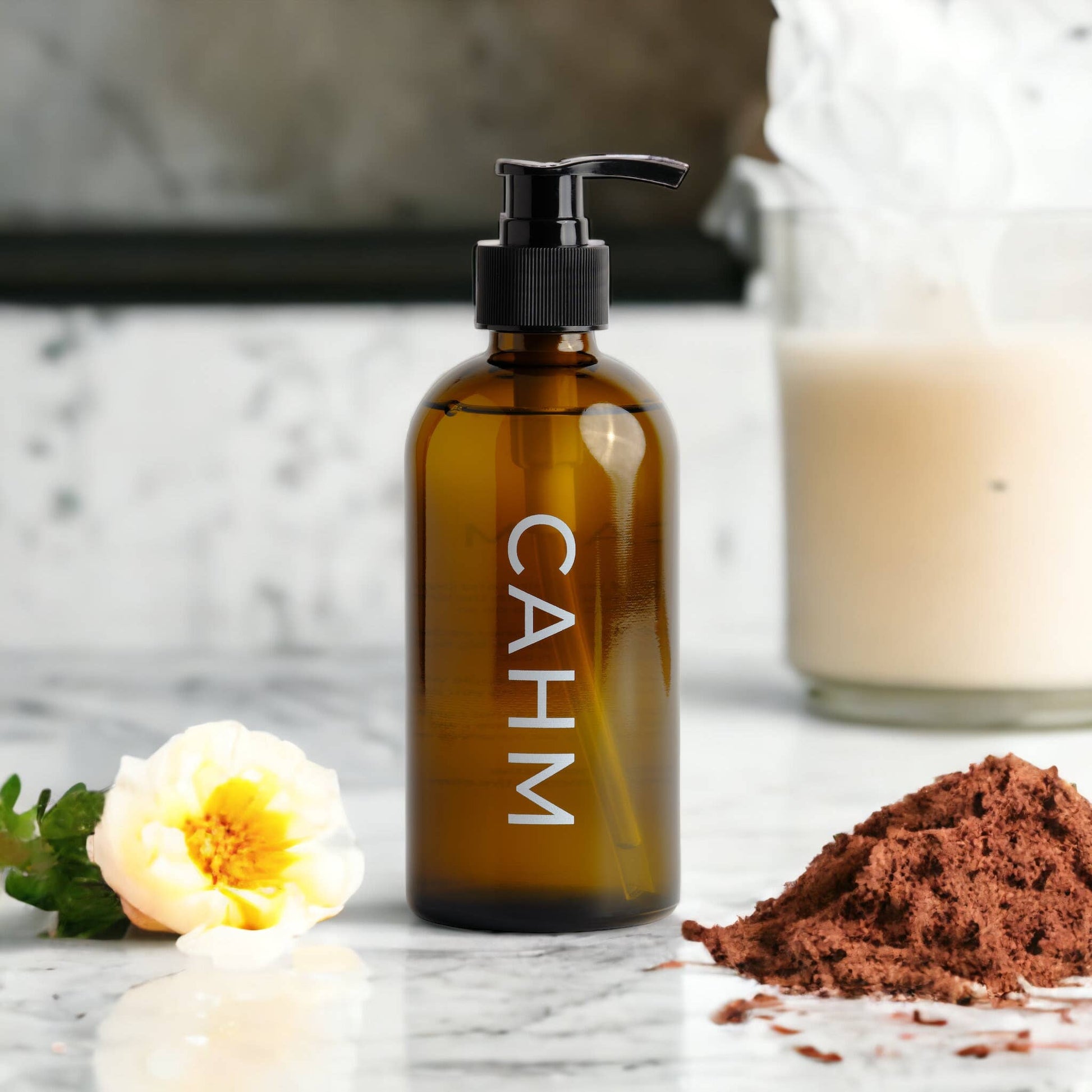 Brown bottle with pump labeled 'CAHM' on a marble surface with a flower and brown powder.