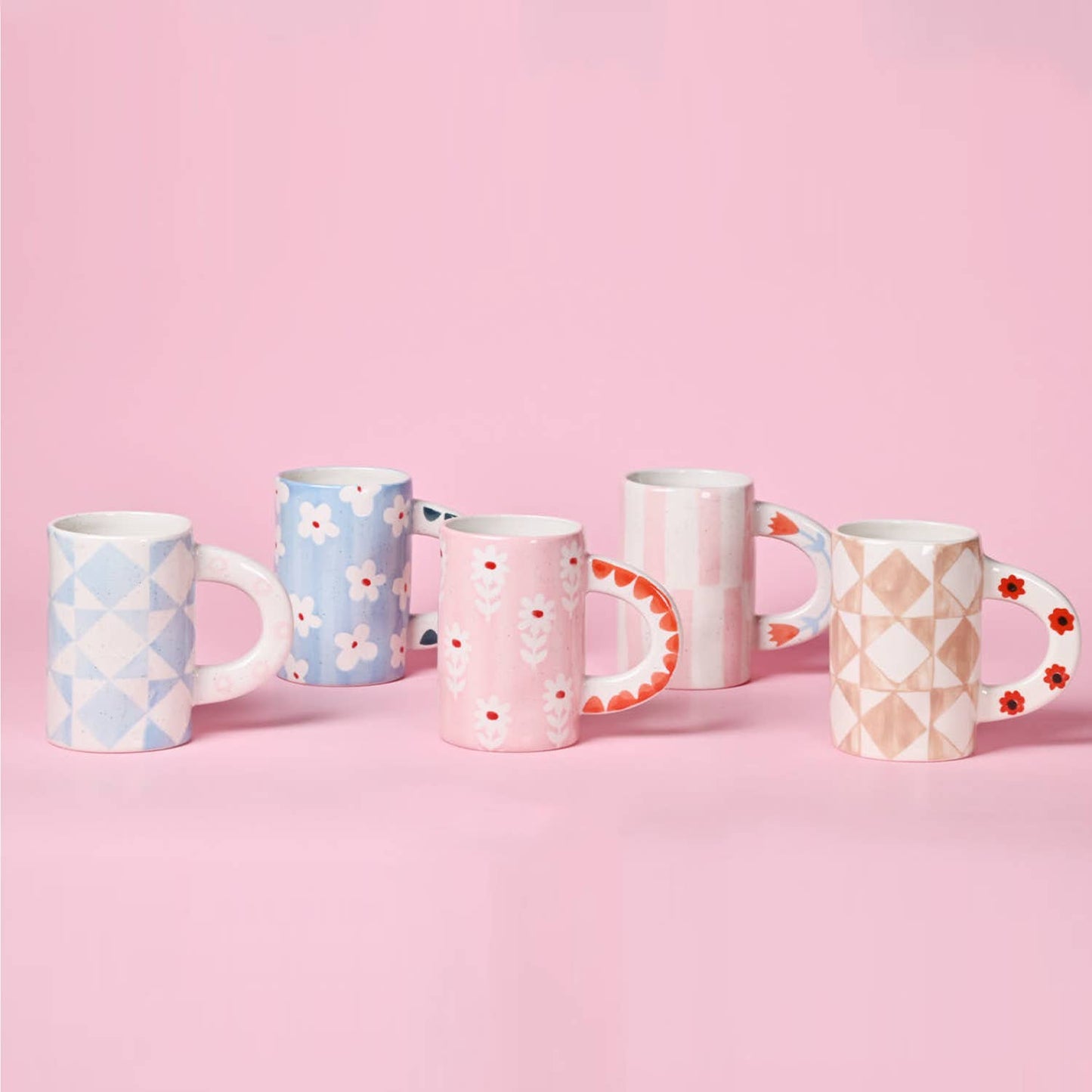 Set of five patterned mugs on a pink background