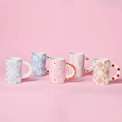 Set of five patterned mugs on a pink background