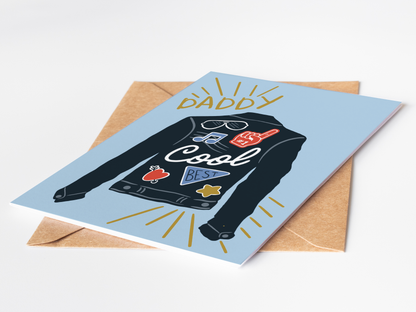 Greeting card with a graphic of a shirt and text 'Daddy Cool' on a blue background, with a brown envelope.