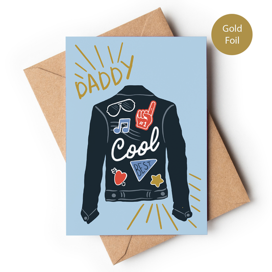 Greeting card with a jacket illustration and 'Daddy Cool' text, featuring gold foil, on a light blue background with a brown envelope.