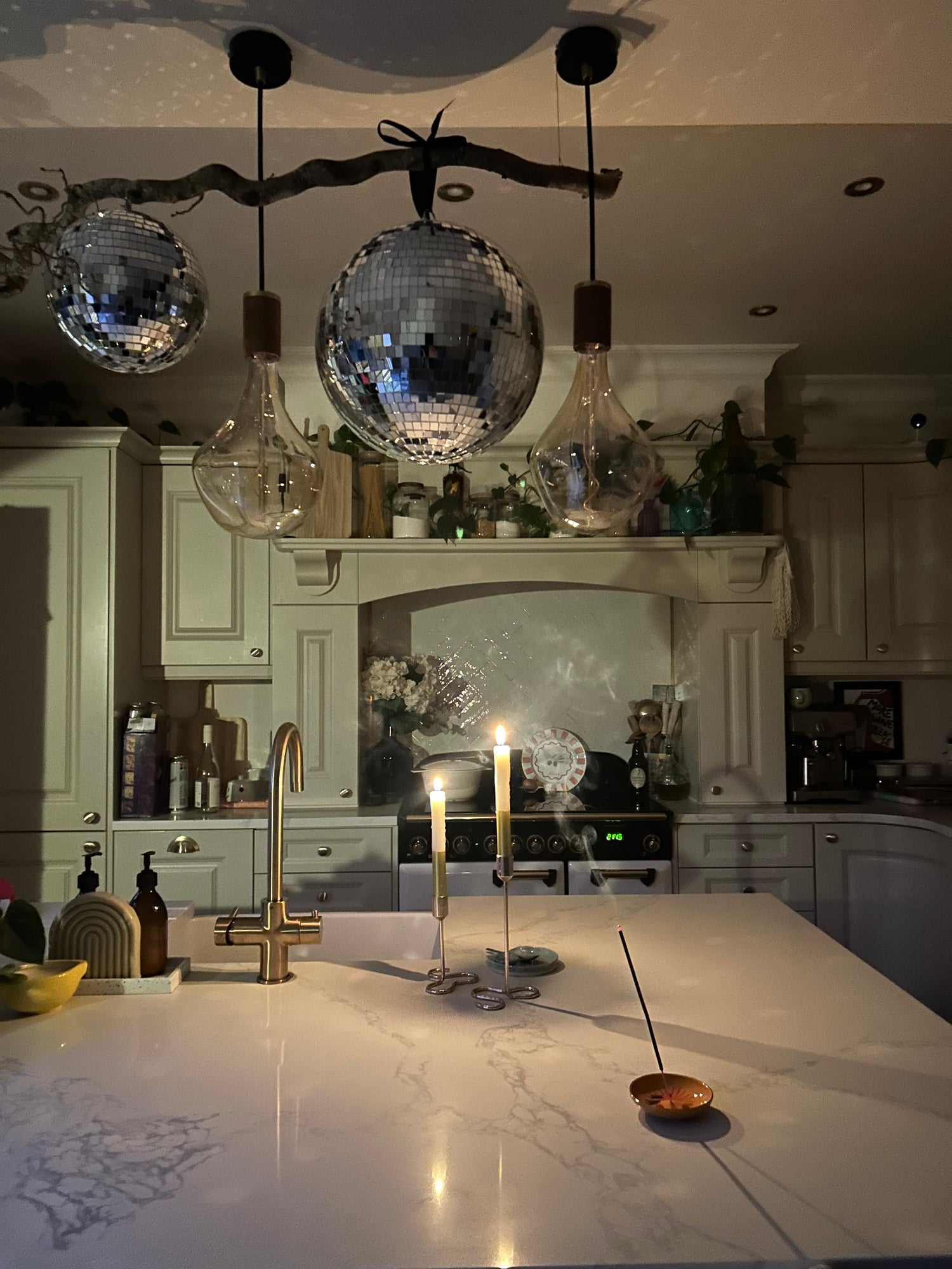Modern kitchen with disco ball pendant lights, marble island, and decorative elements.