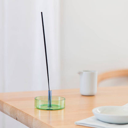 Incense stick in a green holder on a wooden table with a white background