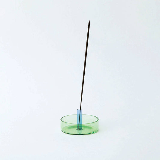 Incense stick in a green holder on a white background