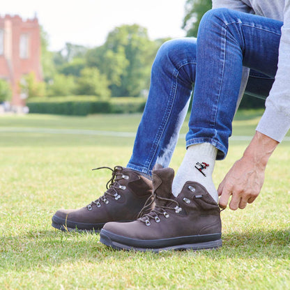 Person wearing brown hiking boots on grass with a blurred background