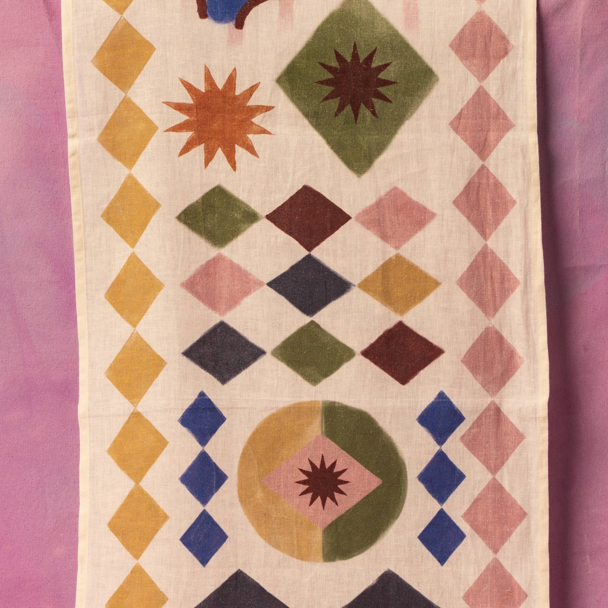 Geometric patterned fabric with colorful diamond shapes on a pink background