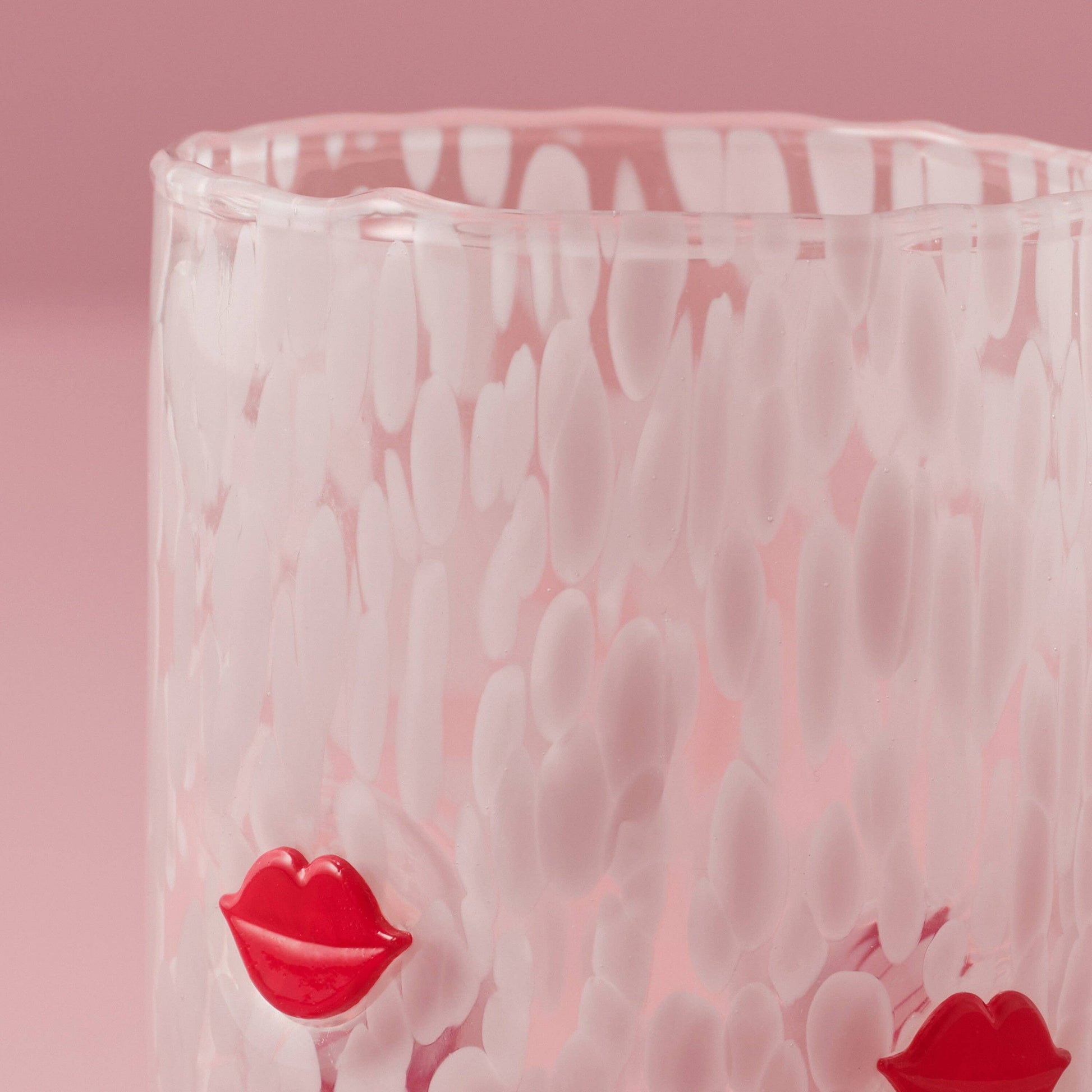 Glass with wavy texture and red lip designs on a pink background