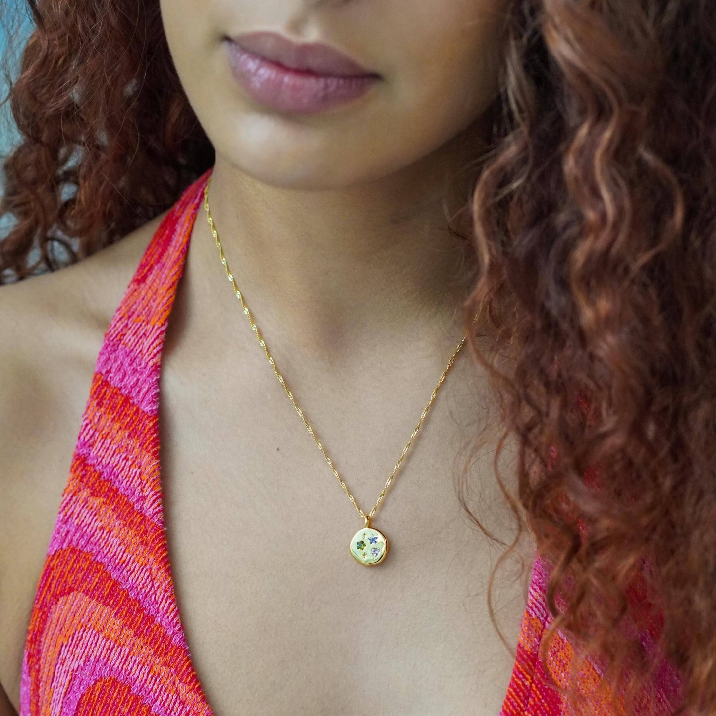 Close-up of a person wearing a gold necklace with a colorful top and hair.