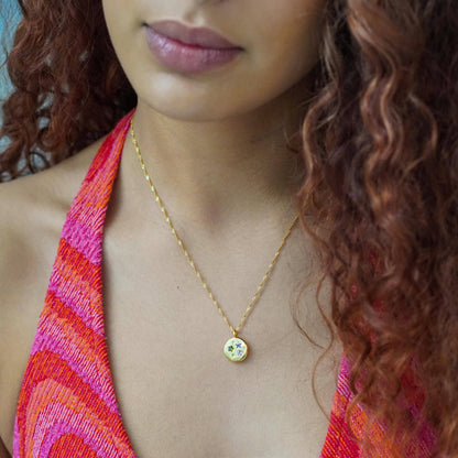 Close-up of a person wearing a gold necklace with a colorful top and hair.