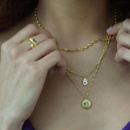Close-up of a person wearing gold necklaces with pendants.