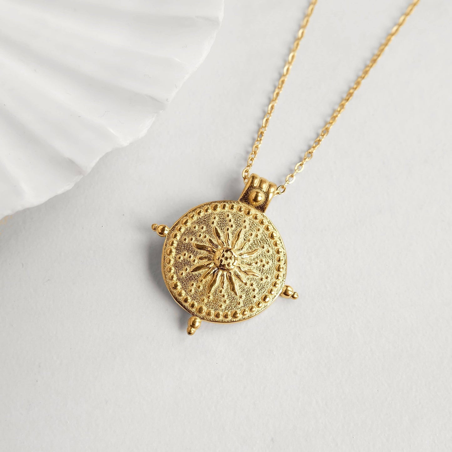 Gold necklace with a detailed pendant on a white background