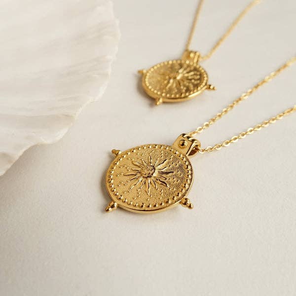 Gold necklaces with circular pendants on a light background