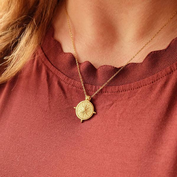 Gold necklace with a pendant on a person wearing a red top