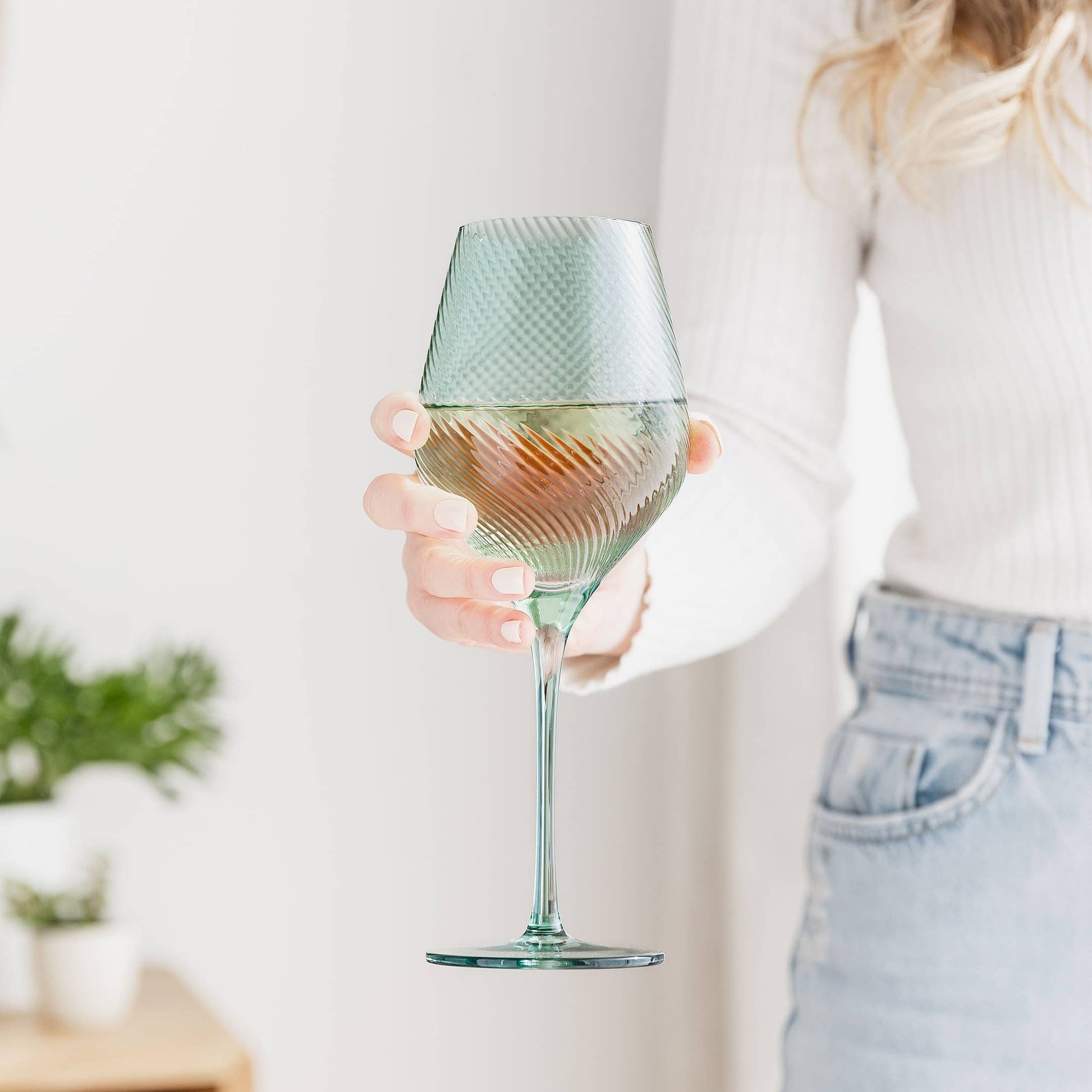 Person holding a textured wine glass with a light-colored background