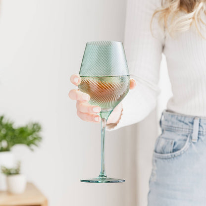 Person holding a textured wine glass with a light-colored background