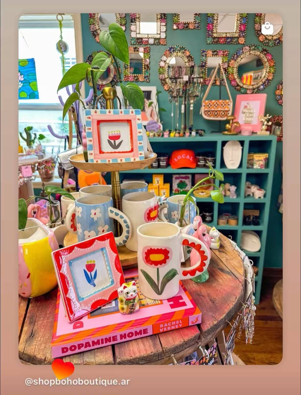 Colorful interior decor items including mugs, frames, and a plant on a wooden table.