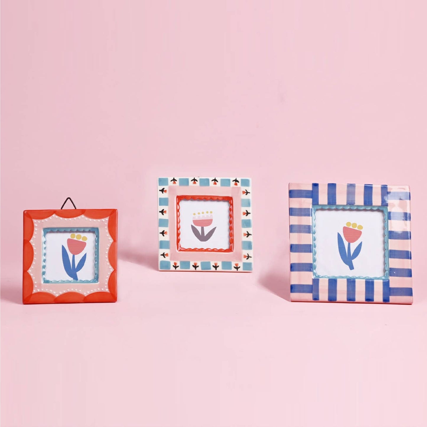 Three decorative picture frames with floral designs on a pink background