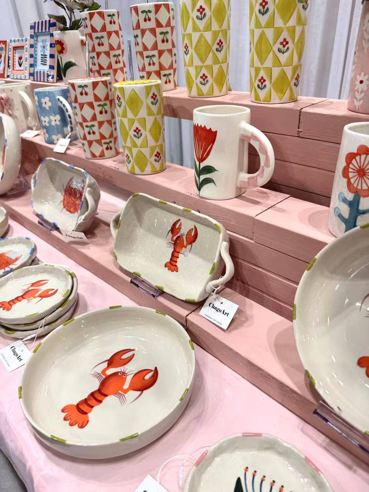 Display of ceramic items with lobster design on a pink shelf