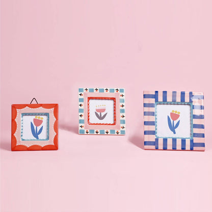 Three decorative picture frames with floral designs on a pink background