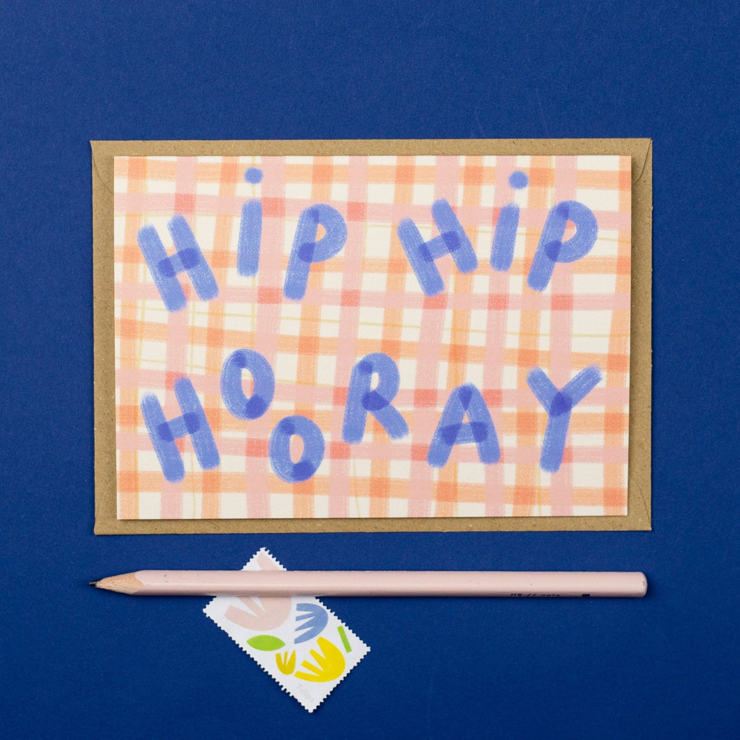 Card with 'HIP HIP HOORAY' text on a checkered background with a pen and cleaning wipe on a blue background