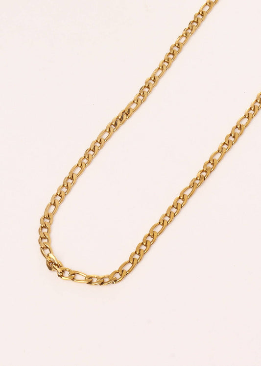 Gold chain necklace on a light pink background