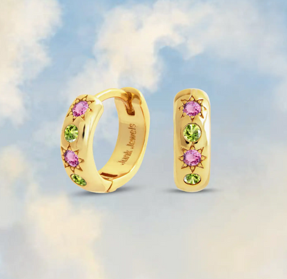 Gold hoop earrings with pink and green gemstones on a soft focus background
