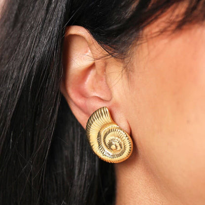 Gold spiral earring worn by a person with dark hair.